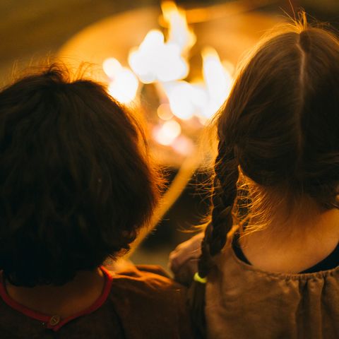 Zwei Kinder schauen in ein Lagerfeuer
